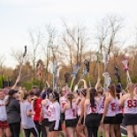 Girls Lacrosse team holding up lacrosse sticks